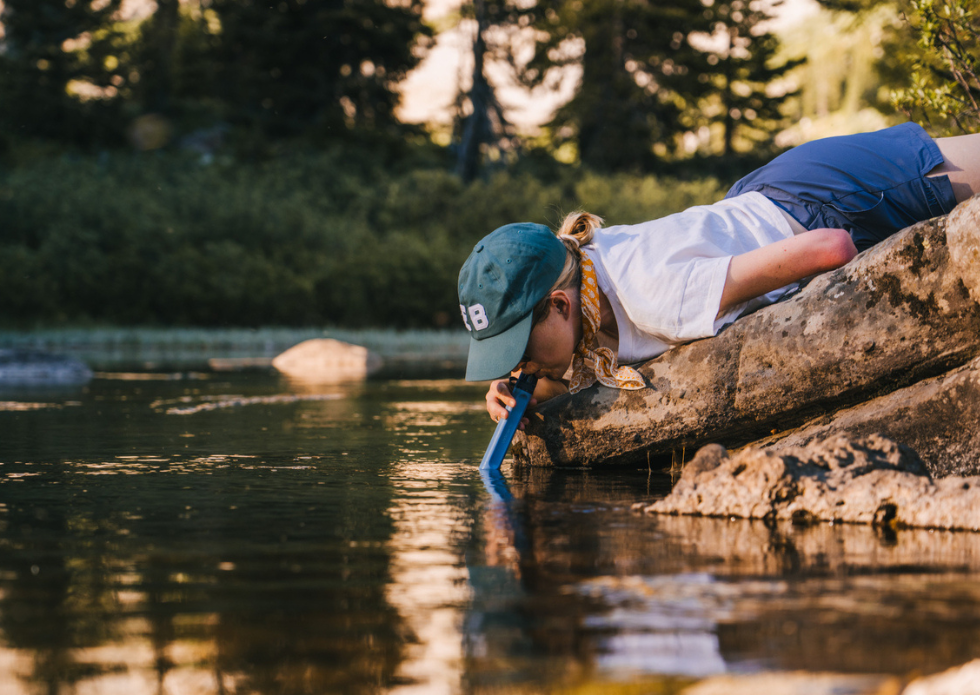 Filtr słomkowy LifeStraw Peak Personal wykorzystywany przez kobietę na brzegu rzeki